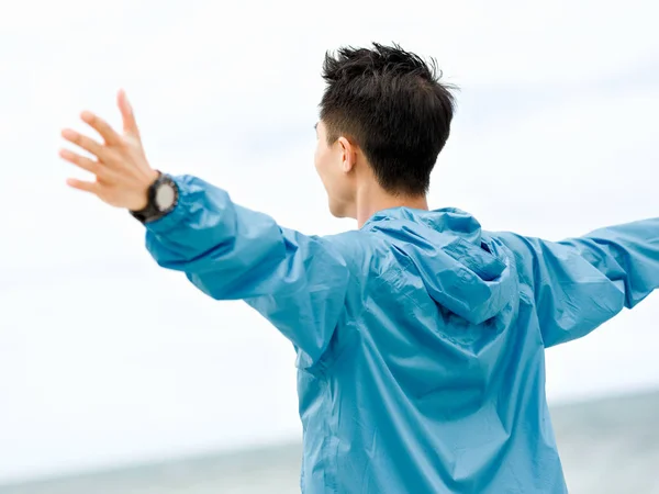 Молодий чоловік з простягнутими руками на пляжі — стокове фото