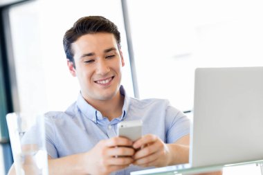 Kendine güvenen genç adam akıllı rahat kıyafet telefon tutarak