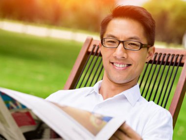 İş adamı parkta bir gazete okuyor