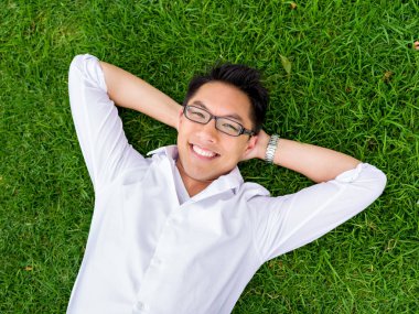Ppretty genç adam beyaz gömlekli bir çim üzerinde rahatlatıcı