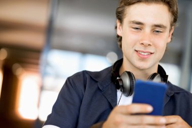 Kendine güvenen genç adam akıllı rahat kıyafet telefon tutarak