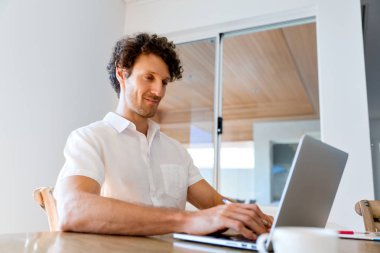 Adam evde dizüstü bilgisayarla çalışıyor.