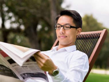 İş adamı parkta bir gazete okuyor