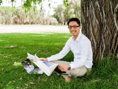 İş adamı parkta bir gazete okuyor