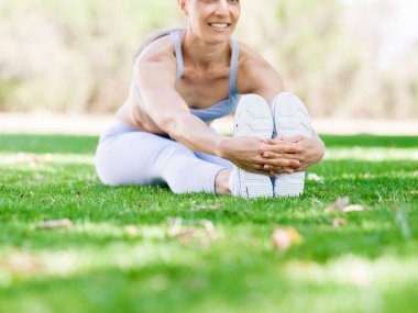 Parkta egzersiz yapan genç bir kadın.