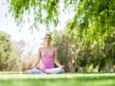Parkta yoga yapan genç kadın.