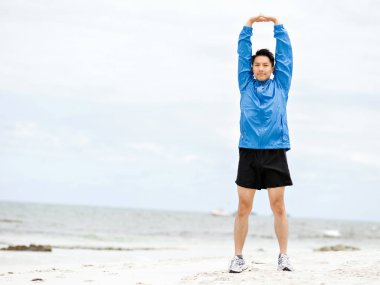 Genç adam sahilde egzersiz yaparak