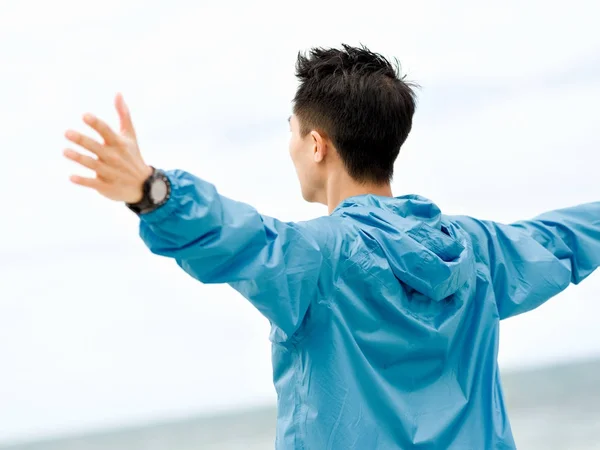 Young man with outstretched arms at the beach — Stock Photo, Image