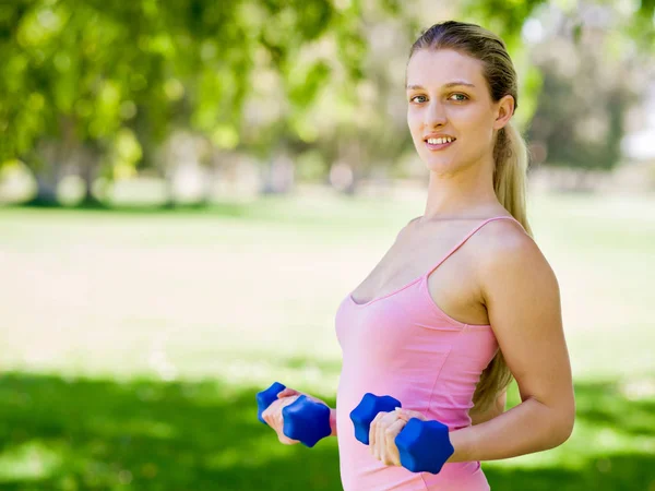 Porträt einer fröhlichen Frau in Fitnessbekleidung, die mit einer Hantel trainiert — Stockfoto