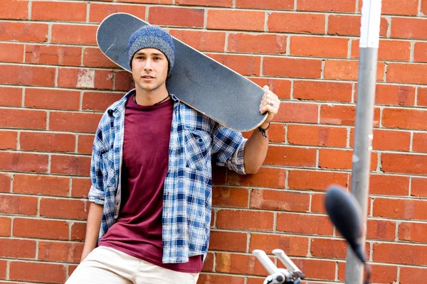 Adolescente com skate ao lado da parede — Fotografia de Stock