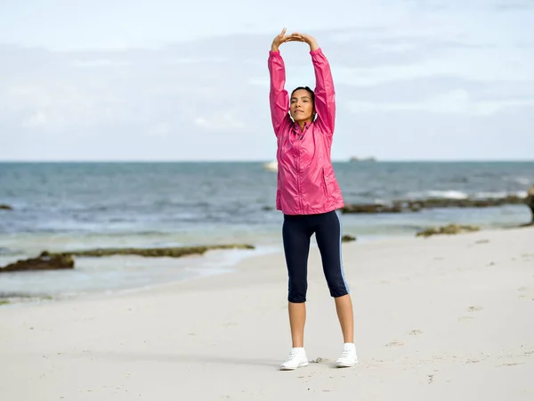 Ung kvinna på stranden gör övningar — Stockfoto