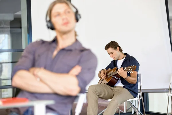 Jovem tocando guitarra no escritório — Fotografia de Stock