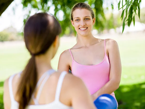 Dwie młode kobiety z siłownią mat rozmowy w parku — Zdjęcie stockowe