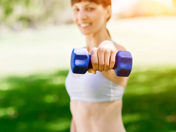 Porträt einer fröhlichen Frau in Fitnessbekleidung, die mit einer Hantel trainiert — Stockfoto