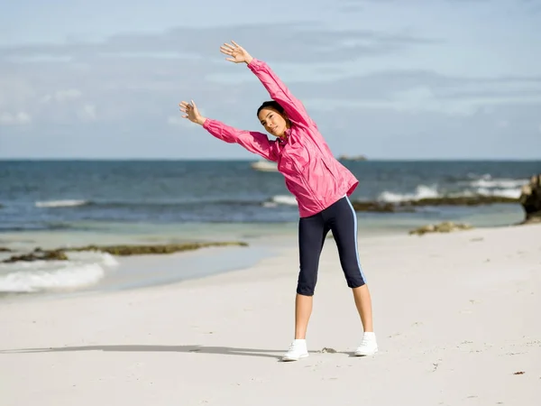 Ung kvinna på stranden gör övningar — Stockfoto