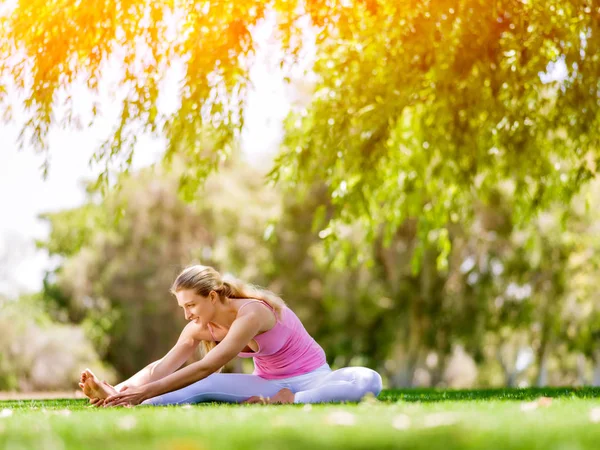 Jonge vrouw doet yoga in het park — Stockfoto