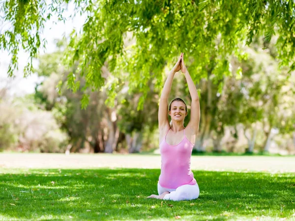 Parkta yoga yapan genç kadın. — Stok fotoğraf