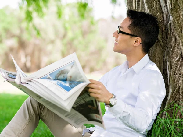 Uomo d'affari che legge un giornale nel parco — Foto Stock