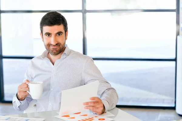 Handsome young man holding paper in office — Stock Photo, Image