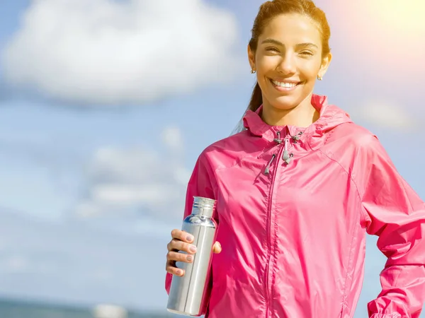 Schönes Mädchen in Sportkleidung trinkt Wasser nach dem Training am Strand — Stockfoto