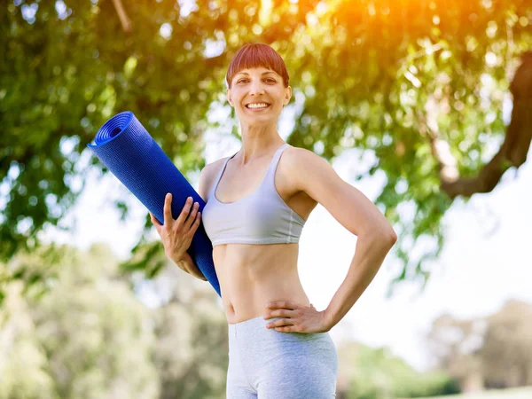 Junge Frau auf einer Turnmatte im Park — Stockfoto