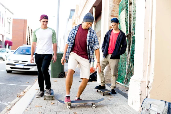 Teenage friends walking at the street with skateboards — Stock Photo, Image