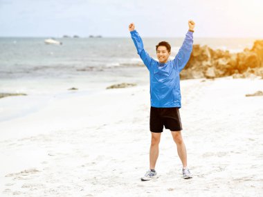 Sahilde uzanmış kolları olan genç adam