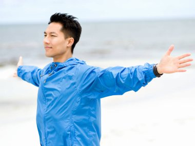 Sahilde uzanmış kolları olan genç adam