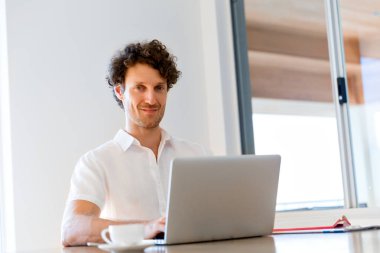 Adam evde dizüstü bilgisayarla çalışıyor.