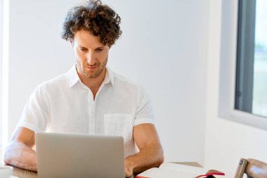 Adam evde dizüstü bilgisayarla çalışıyor.