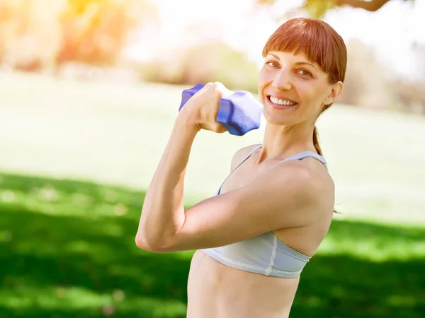 Portret van vrolijke vrouw bij de uitoefening van fitness slijtage met dumbbell — Stockfoto