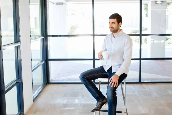 Jeune homme d'affaires assis sur un tabouret au bureau — Photo