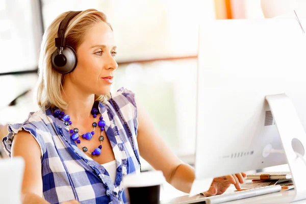 Mujer joven en la oficina con auriculares —  Fotos de Stock