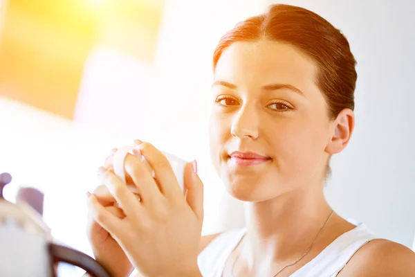 Glückliche junge Frau mit einer Tasse Tee oder Kaffee zu Hause — Stockfoto