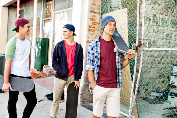 Amigos adolescentes caminando por la calle con patinetas — Foto de Stock