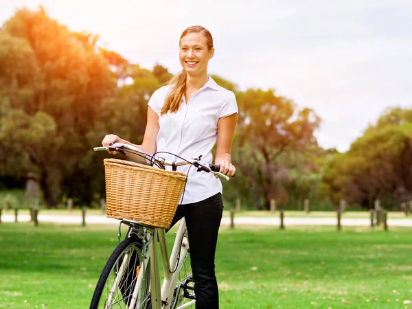 Красивая молодая блондинка с велосипедом в парке — стоковое фото