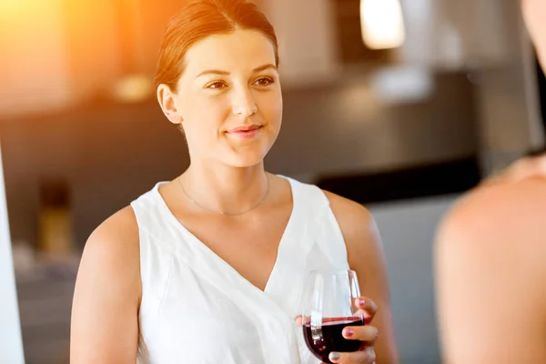 Giovane donna con la sua amica che tiene un bicchiere di vino in casa — Foto Stock