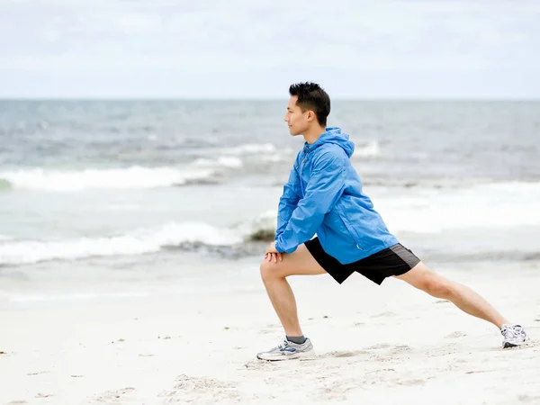 Jonge man doen oefening op het strand — Stockfoto