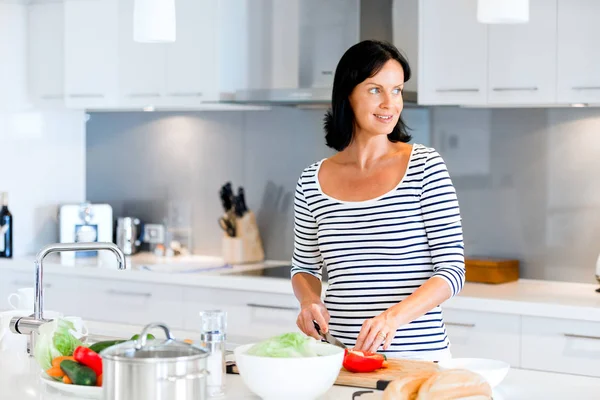 Mulher bonita de pé na cozinha e sorrindo — Fotografia de Stock