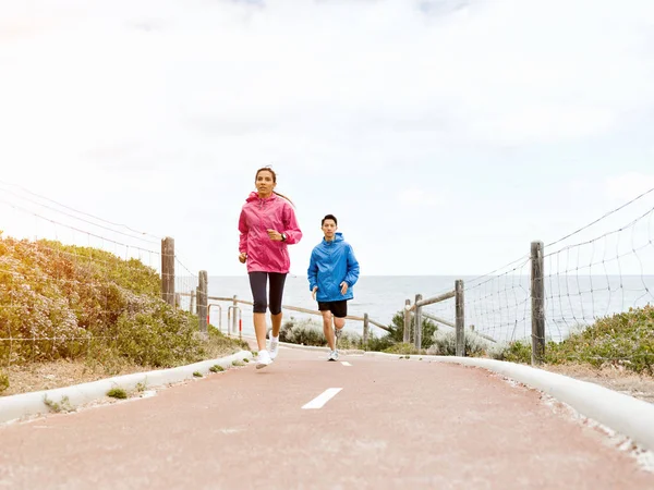 Mladý pár běží podél mořského pobřeží — Stock fotografie