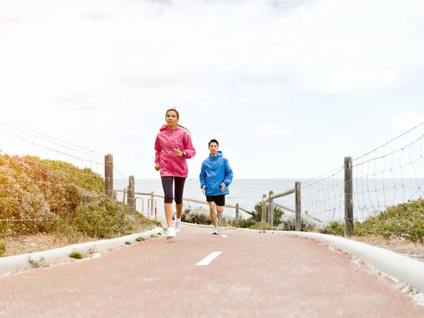 Pareja joven corriendo a lo largo de la orilla del mar — Foto de Stock