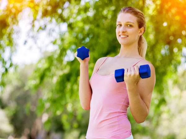 Portrait of cheerful woman in fitness wear exercising with dumbbell — Stock Photo, Image