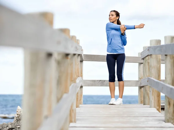 Jonge vrouw op het strand doen oefeningen — Stockfoto