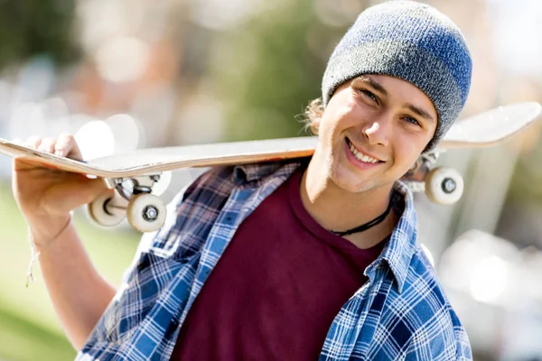 Adolescente com skate de pé ao ar livre — Fotografia de Stock