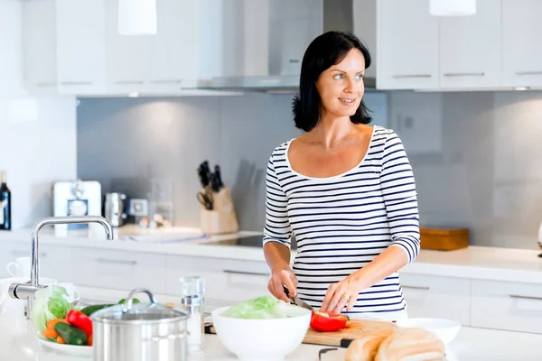 Schöne Frau steht in der Küche und lächelt — Stockfoto