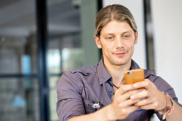 Впевнений молодий чоловік у розумному повсякденному носінні тримає телефон Ліцензійні Стокові Фото