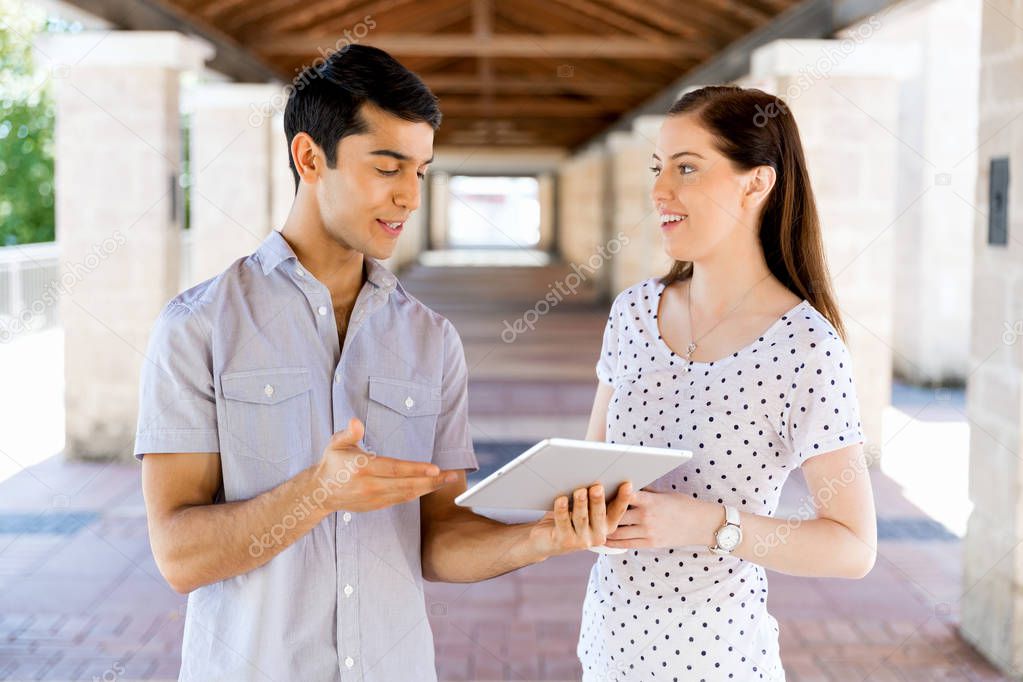 Two young students outdoors with tablet