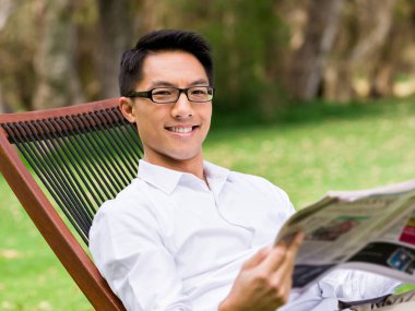 İş adamı parkta bir gazete okuyor