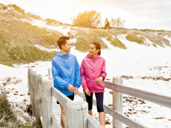 Ung man och kvinna i sportkläder promenader på stranden — Stockfoto