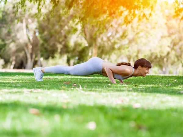 Ung kvinna motionerar i parken — Stockfoto